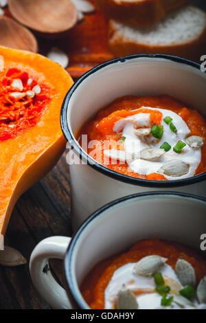 Hausgemachte Winter-Kürbis-Suppe in weiße Tasse auf rustikalen Holztisch Stockfoto