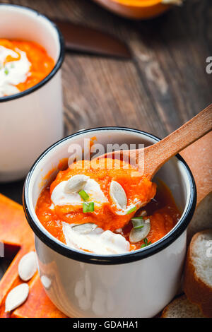 Hausgemachte Winter-Kürbis-Suppe in weiße Tasse auf rustikalen Holztisch Stockfoto