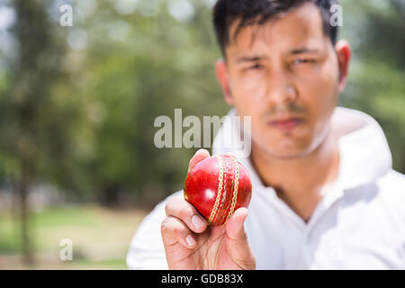 Ein indischer Junge Mann Bowler holding Ball spielen Kricket in Spielplatz Stockfoto