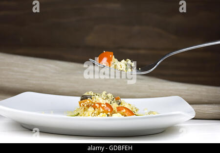 Couscous in einem weißen Keramikplatte mit hölzernen Hintergrund Stockfoto