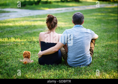 Liebespaar sitzen auf dem Rasen im Sommer Park zurück Stockfoto