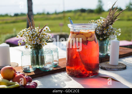 Frisches Kompott, Obst, Kerzen und Blumen auf Holztisch Closeup. Selektiven Fokus. Beutiful Dekoration im Boho-Stil. Stockfoto