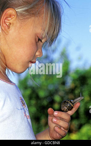 Mädchen mit braunen Garten Schnecke Helix Aspersa am Finger Stockfoto