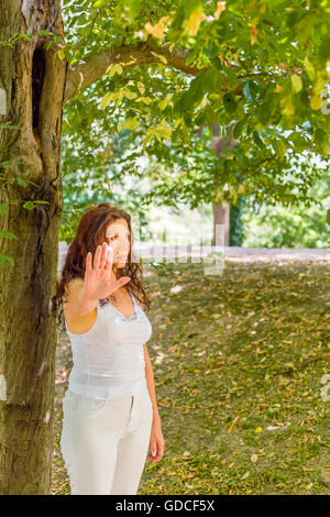 Stoppen Sie und sprechen Sie mit meiner Handgeste von dralle Frau über 40 mit negativen Gefühlen gegen grünen Garten Hintergrund mit Textfreiraum Stockfoto