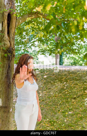 Stoppen Sie und sprechen Sie mit meiner Handgeste von dralle Frau über 40 mit negativen Gefühlen gegen grünen Garten Hintergrund mit Textfreiraum Stockfoto