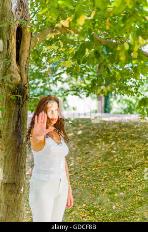 Stoppen Sie und sprechen Sie mit meiner Handgeste von dralle Frau über 40 mit negativen Gefühlen gegen grünen Garten Hintergrund mit Textfreiraum Stockfoto