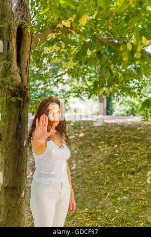 Stoppen Sie und sprechen Sie mit meiner Handgeste von dralle über 40 Frau, die in der Kamera mit negativen Gefühlen gegen grünen Garten Hintergrund mit Textfreiraum Stockfoto