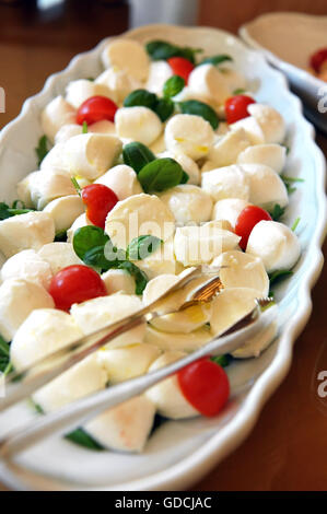 Teller mit italienischen Caprese-Salat mit Mozzarella, Basilikum und Tomaten auf einem Buffet-Tisch mit einer Zange zum servieren Stockfoto