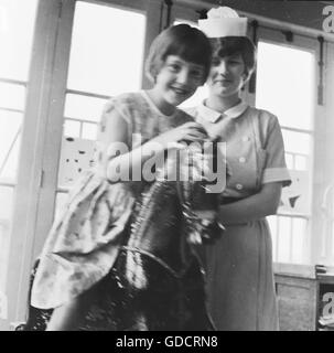 Krankenschwester mit einem Kind auf Schaukelpferd.  Krankenschwestern in ein Wohngebiet Lehrkrankenhaus in Leicester c1962. Foto von Tony Henshaw Stockfoto