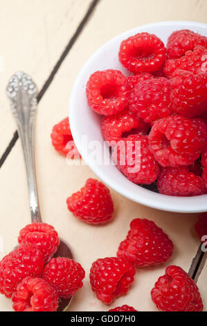 Reihe von frischen Himbeeren in eine Schüssel geben und weiß rustikalen Holztisch Stockfoto