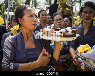 Ubud, Bali, Indonesien. 15. Juli 2016. Frauen warten auf Angebote in die Sarkophage zu legen, die auch die Bildnisse des verstorbenen während der Gemeinschaft breite Feuerbestattung Gianyar halten. Die meisten Menschen auf Bali sind Hindus. Traditionelle Feuerbestattungen in Bali sind sehr teuer, so dass die Gemeinden in der Regel eine Masse Einäscherung etwa alle fünf Jahre halten. Die meisten der Masse Feuerbestattungen in Bali finden Ende Juni oder Anfang Juli statt. Gianyar, einem kleinen Dorf ca. 30 Minuten von Ubud, statt ihre Dorf breite Feuerbestattung Freitag. Die Gemeinschaft breite Masse Einäscherung in Ubud ist Samstag. (Kredit-Bild: © Jack Kurtz Stockfoto