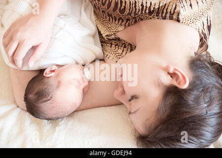 Mutter auf Bett liegend mit Neugeborenen Baby boy Stockfoto