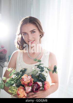 Porträt einer lächelnden jungen Frau mit Blumenstrauss Stockfoto