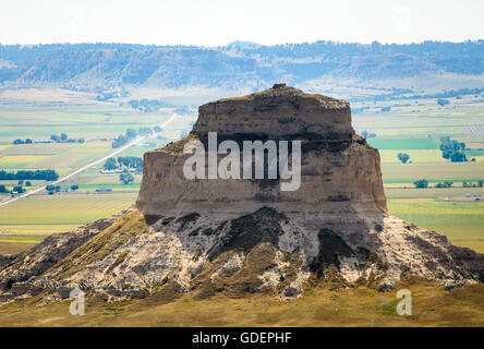 Ein schmaler schlammiger Bach windet sich zwischen dichten grünen Seggen und Schilf hin zu fernen niedrigen Buttes im Agate Fossil Beds National Monument, Nebraska. Stockfoto