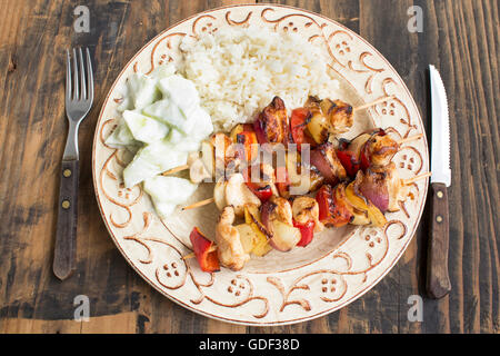 Spieße mit Hühnerfilet mit Gemüse, Salat, Gurke und Reis. Stockfoto