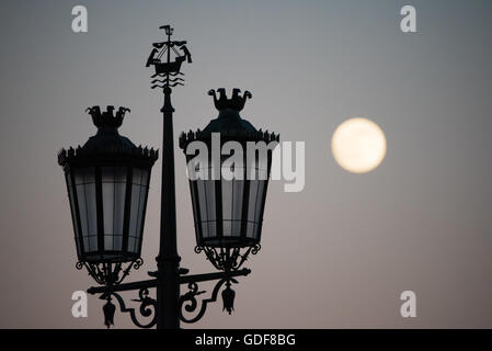 Lissabon, Portugal - Silhouette einer Straßenlaterne am Praça Comércio, mit dem Vollmond im Hintergrund. Bekannt als Commerce Square in englischer Sprache, ist die Praça Do Comércio einen historischen Platz in Lissabon Pombaline Downtown District, direkt am Tejo-Fluss. Stockfoto