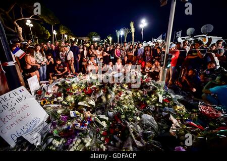 Menschen versammeln sich an der Promenade des Anglais, Nizza, als französische Detektive sind heute Abend versuchen, die Umstände zusammenzusetzen, die mindestens 84 Menschen tot verließ und Noten nach einem Terroristen absichtlich verletzt fuhr einen LKW in Meuterei auf der feiernden vor wird in eine Pattsituation mit bewaffneten Polizisten tödlich verwundet. Stockfoto