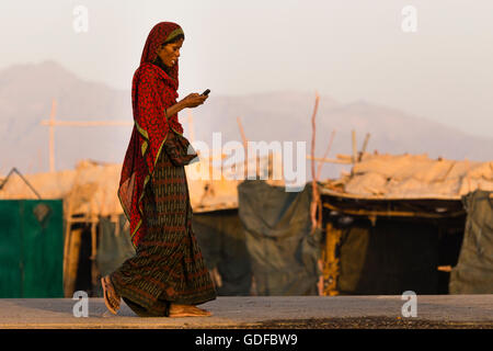 Ferne Frau mit Handy in die ferne Dorf von Ahmed Ale, Danakil-Senke, Äthiopien Stockfoto