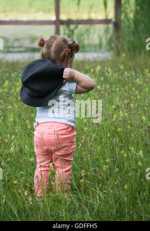 AMSTERDAM, Niederlande - JULI 9, 2016: Unbekanntes Mädchen 18 Monate alten mit roten Haaren Wlaking grün grass Wairing einen Hut auf Stockfoto