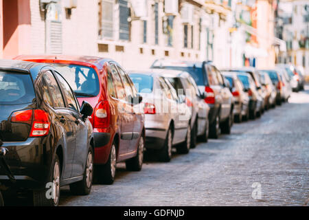 Autos parken auf Straße In europäischen Stadt im sonnigen Sommertag. Hintergrund Stockfoto