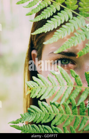 Close Up Portrait einer jungen glücklich Schönheit rotes Haar Mädchen Frau hält Farn Blatt bis zu Gesicht im Sommer Waldpark Stockfoto