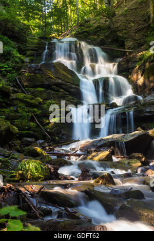 großen Wasserfall mit riesigen Felsbrocken im grünen Wald am Sommermorgen Stockfoto
