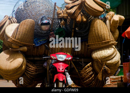 Ein Korb Anbieter Anhänger abgeschleppt von einem Motorrad ist voll geladen und parkten auf einer Stadtstraße in Chork Village, Kambodscha. Stockfoto