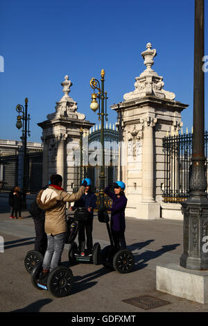 Asiatische Touristen auf Segway-Tour vor dem Haupttor der Königspalast, Plaza De La Armeria, Madrid, Spanien Stockfoto