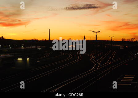 Die Sonne geht über Bahngleise am Bahnhof in Deutschland Stockfoto