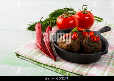 Gegrillte Frikadellen mit Chili-Pfeffer Scheiben in gusseisernen Pfanne serviert.  Gegrillte Grillen Hackbraten. Grill-Frikadellen. Stockfoto