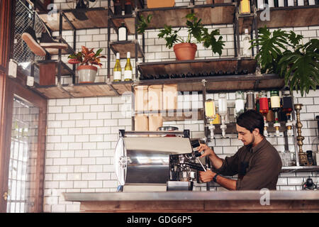 Richtungskontrolle Ansicht der männlichen Barista eine Tasse Kaffee zu machen. Junger Mann hinter der Café Zähler bereitet Kaffee mit Kaffee