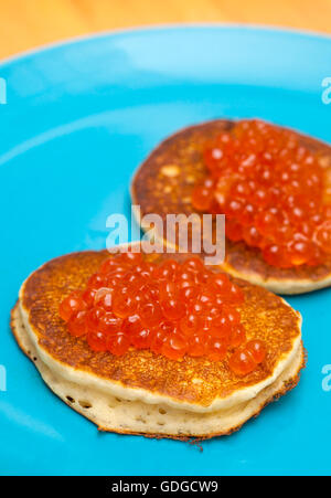 dicke Pfannkuchen mit Lachsrogen auf blaue Platte Stockfoto