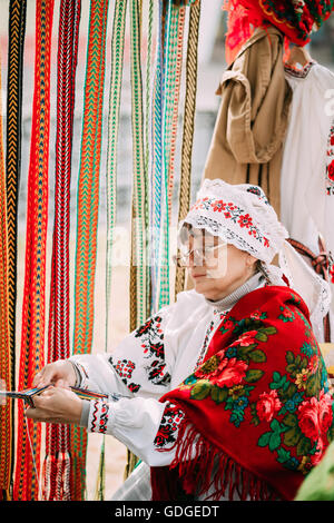 Gomel, Weißrussland - 12. September 2015: Frau in nationalen belarussischen Tracht weben Riemen Stockfoto