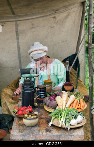 Mittelalterliche Frau Reenactor und Tabelle von Lebensmitteln bei Tewkesbury mittelalterlichen Festspielen 2016, Gloucestershire, England. Stockfoto