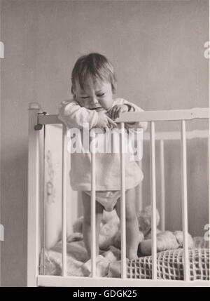 Baby stehend in ihrem Kinderbett Weinen Vintage Black & weiß der 1950er Jahre Stockfoto