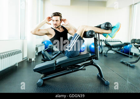 Junger Mann, Übungen für die Bauchmuskeln in der Turnhalle Stockfoto