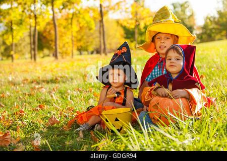 Kinder in Halloween-Kostümen, die sitzen auf dem Rasen Stockfoto