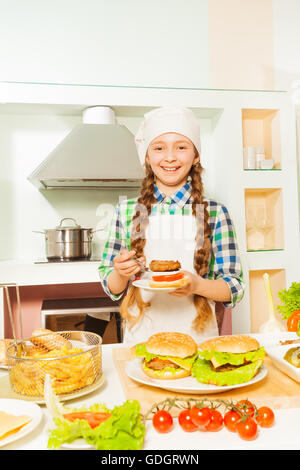 Lächelndes Mädchen Vorbereitung Hamburger in der Küche Stockfoto