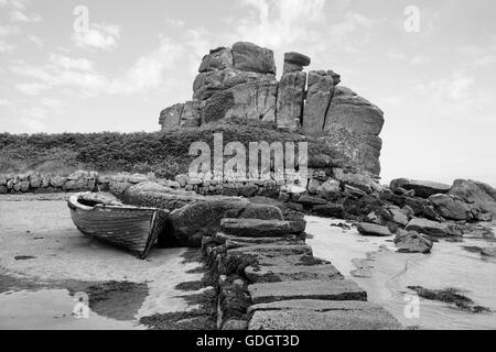 Verlassene Boot durch einen Steg und Dick's Carn (aka der geladenen Camel), Porth Hellick, St. Mary's, Isle of Scilly, UK. Schwarz und Weiss Stockfoto