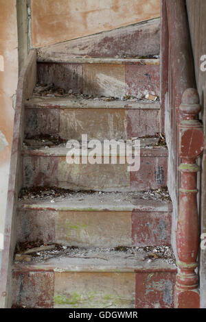 Vertikale Aufnahme einer vergessenen Holztreppe in einem leeren verlassenen Haus. Stockfoto