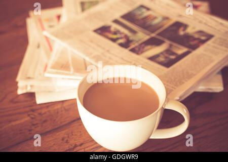 Tasse Kaffee und Zeitung mit warmen Vintage-Ton Stockfoto