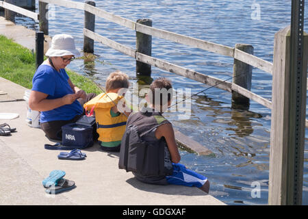 Großmutter, Fischen mit zwei jungen auf einem Pier an der öffentlichen Marina in Whitehall, Michigan. Stockfoto