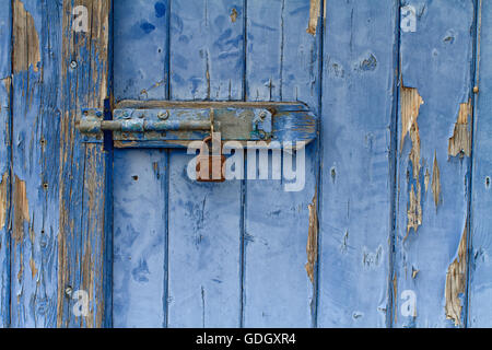 Abblätternde blau bemalte Holztür mit rostigen Vorhängeschloss Stockfoto