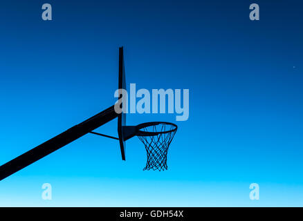 Basketball Hoop-Silhouette bei Sonnenuntergang mit einem blauen Himmel Stockfoto