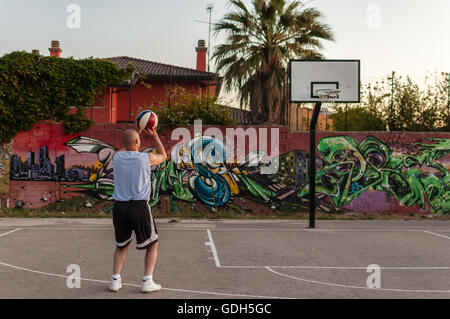 Basketballspieler in Stadt Spielplatz bei Sonnenuntergang Stockfoto