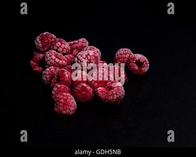 Himbeeren gefroren auf einem schwarzen Stein Tisch Stockfoto