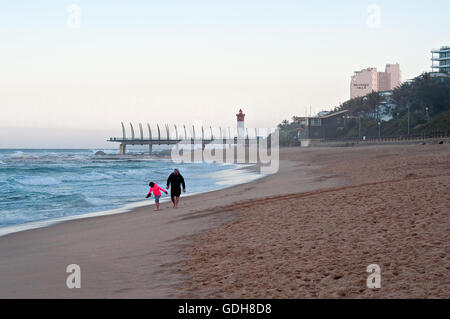 DURBAN, Südafrika - 11. Juli 2016: Menschen am Strand von Umhlanga Rocks, mit dem Millennium Pier und dem Leuchtturm in den Rücken Stockfoto