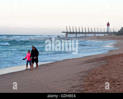 DURBAN, Südafrika - 11. Juli 2016: Menschen am Strand von Umhlanga Rocks, mit dem Millennium Pier und dem Leuchtturm in den Rücken Stockfoto