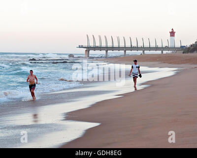 DURBAN, Südafrika - 11. Juli 2016: Menschen am Strand von Umhlanga Rocks, mit dem Millennium Pier und dem Leuchtturm in den Rücken Stockfoto