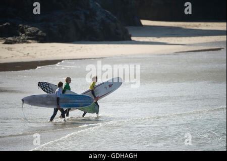 Drei Surfer tragen Longboards in der Brandung Stockfoto